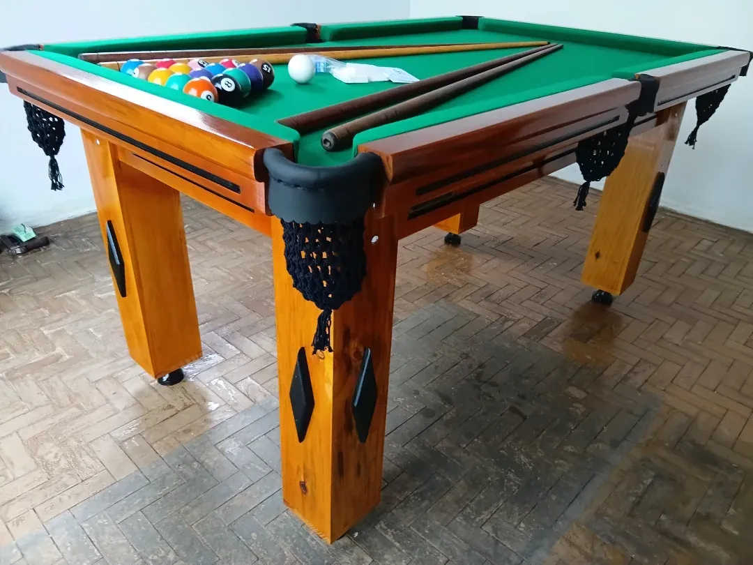 Mesa de bilhar com pano verde, bolas coloridas e tacos, acabamento madeira envernizada.