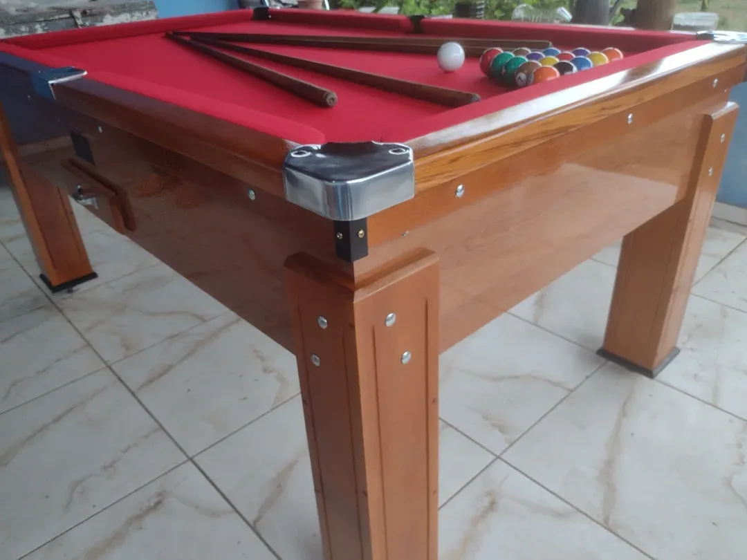 Mesa de bilhar JHP Bilhares com pano vermelho, estrutura de madeira envernizada e cantoneiras metálicas.