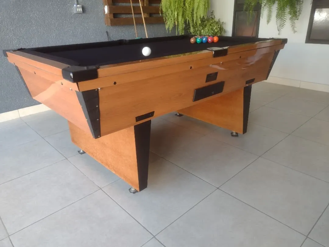 Mesa de sinuca em madeira com pano preto, caçapas pretas e bolas coloridas alinhadas.