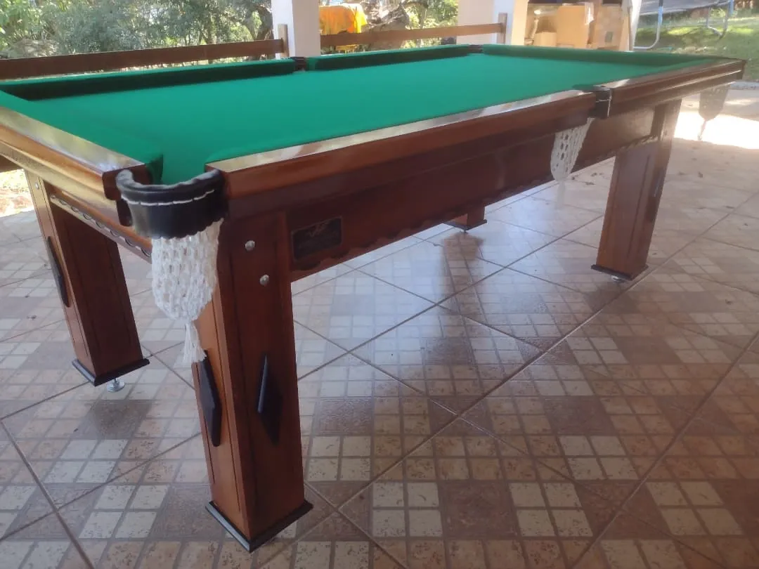 Mesa de sinuca de madeira clara com pano verde, caçapas com rede branca e acabamento premium.