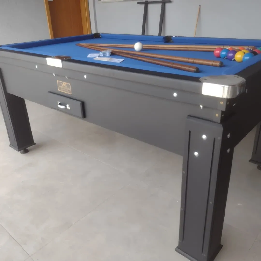 Mesa de sinuca preta com pano azul, tacos de madeira e bolas coloridas alinhadas.